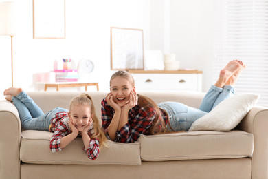 Photo of Happy mother and little daughter having fun on sofa at home
