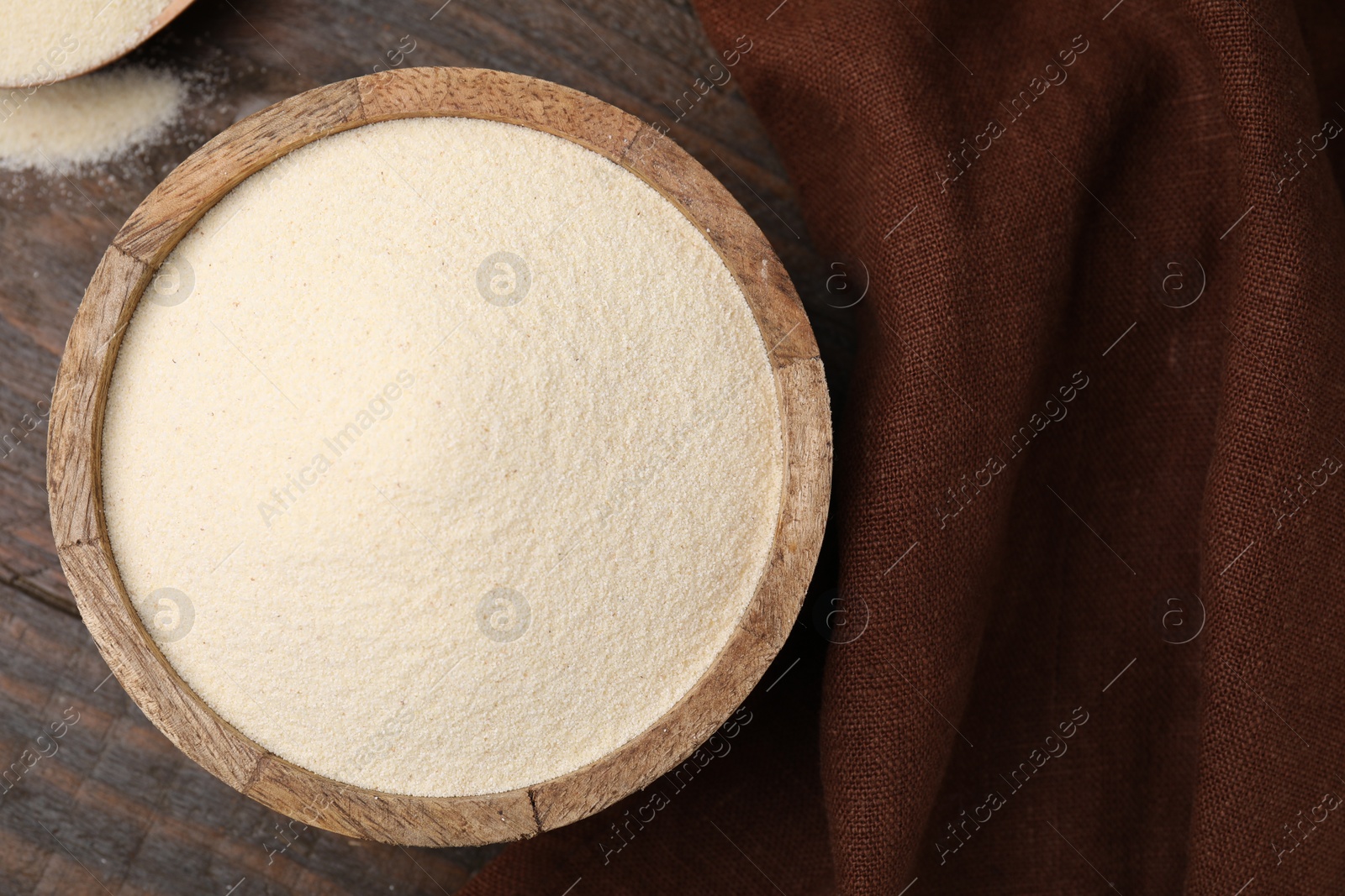 Photo of Uncooked organic semolina in bowl on wooden table, top view