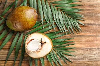 Photo of Fresh green coconuts and palm leaves on wooden table