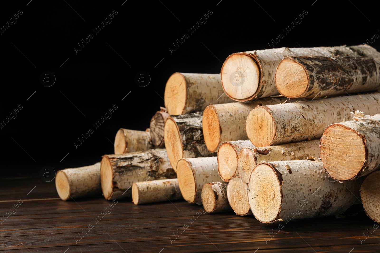 Photo of Cut firewood on table against black background