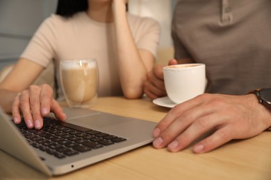 Photo of Couple with coffee and laptop at cafe in morning, closeup
