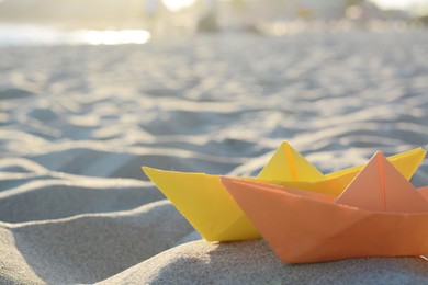 Photo of Colorful paper boats on sand outdoors, space for text