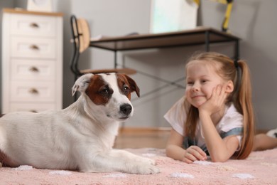 Photo of Cute little girl with her dog on floor at home. Childhood pet