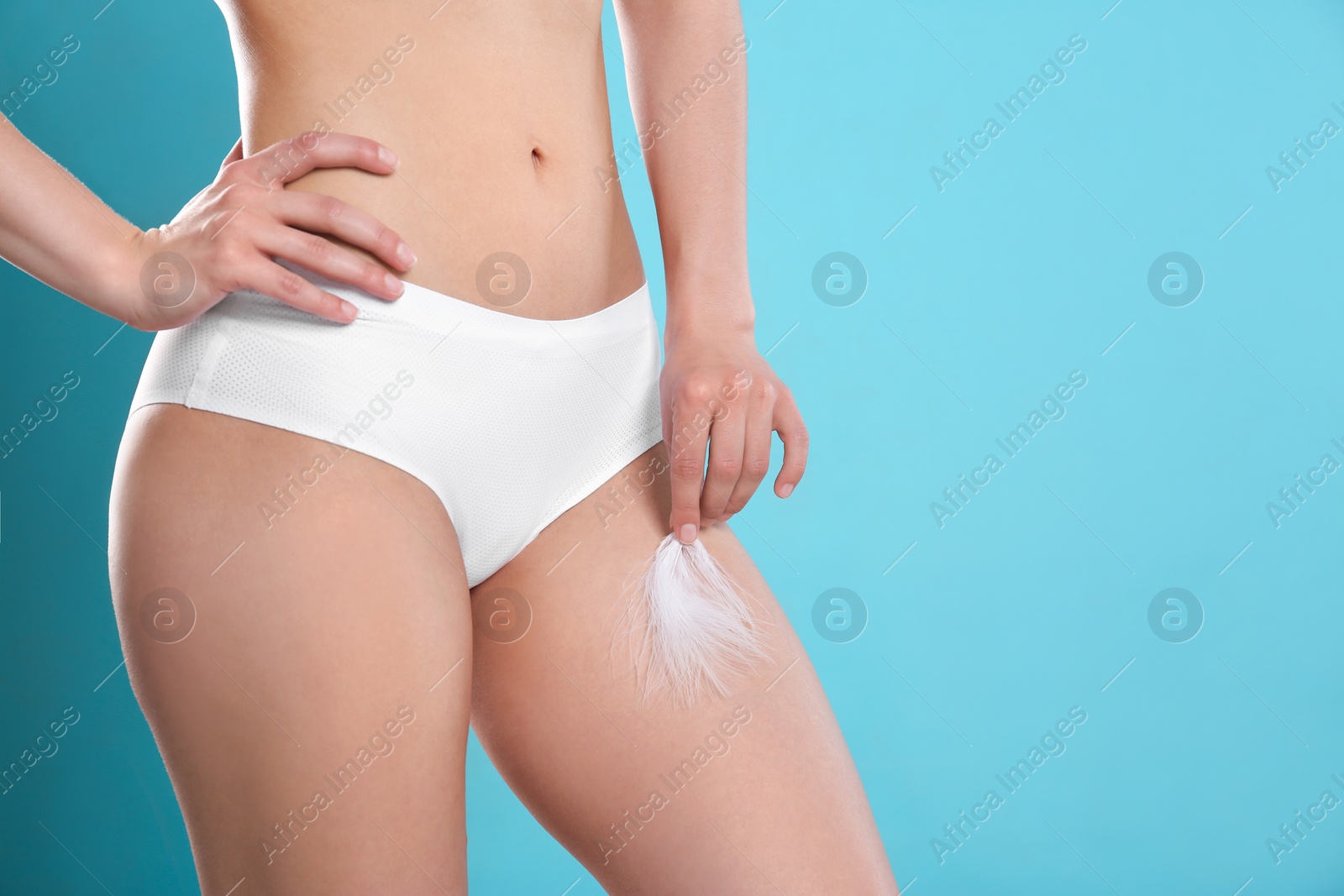 Photo of Closeup of woman touching leg with feather on blue background, space for text. Epilation procedure