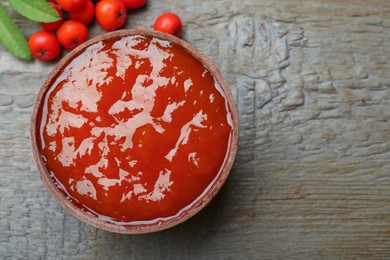 Photo of Delicious rowan jam and berries on wooden table, flat lay. Space for text