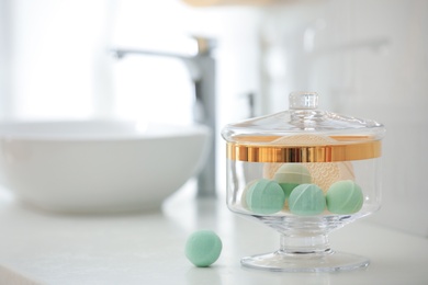 Photo of Jar with bath bombs and bath sponge on white countertop indoors