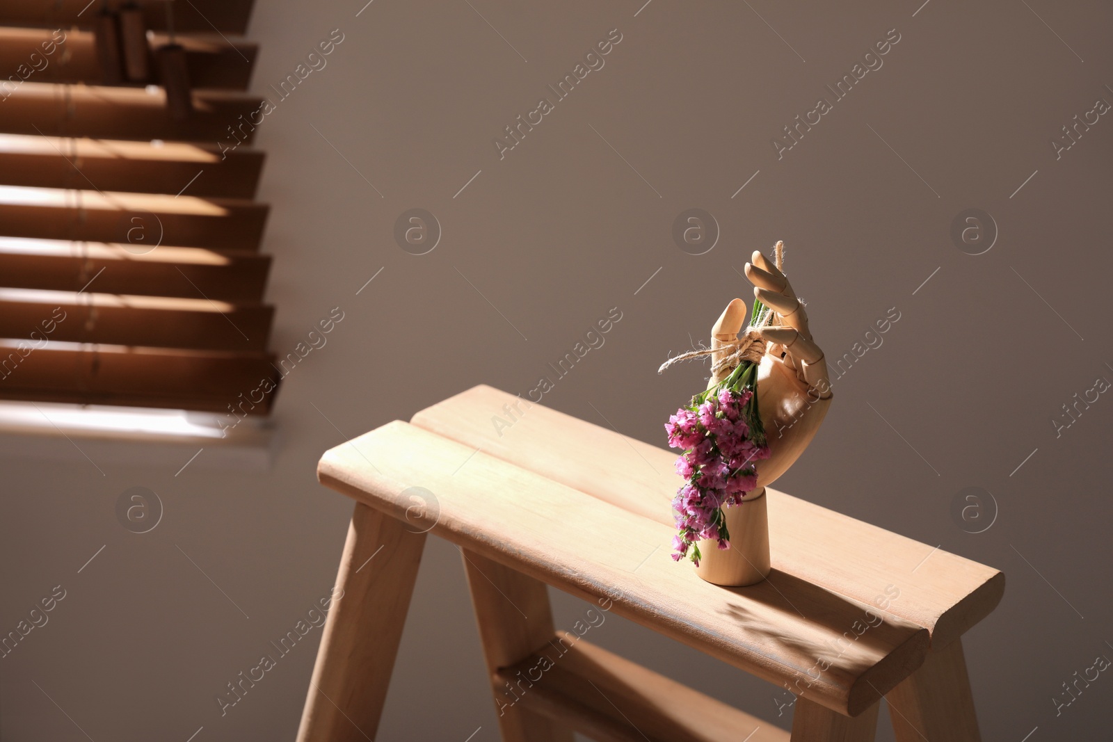 Photo of Decorative hand with flowers on wooden stand indoors, space for text. Interior design