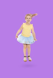 Happy cute girl jumping on violet background