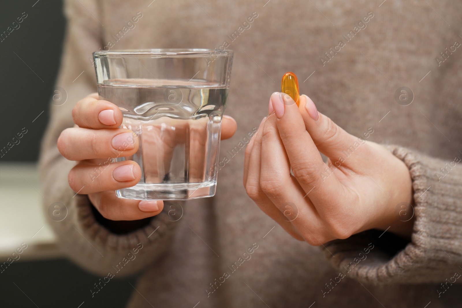 Photo of Woman holding glass of water and pill, closeup view