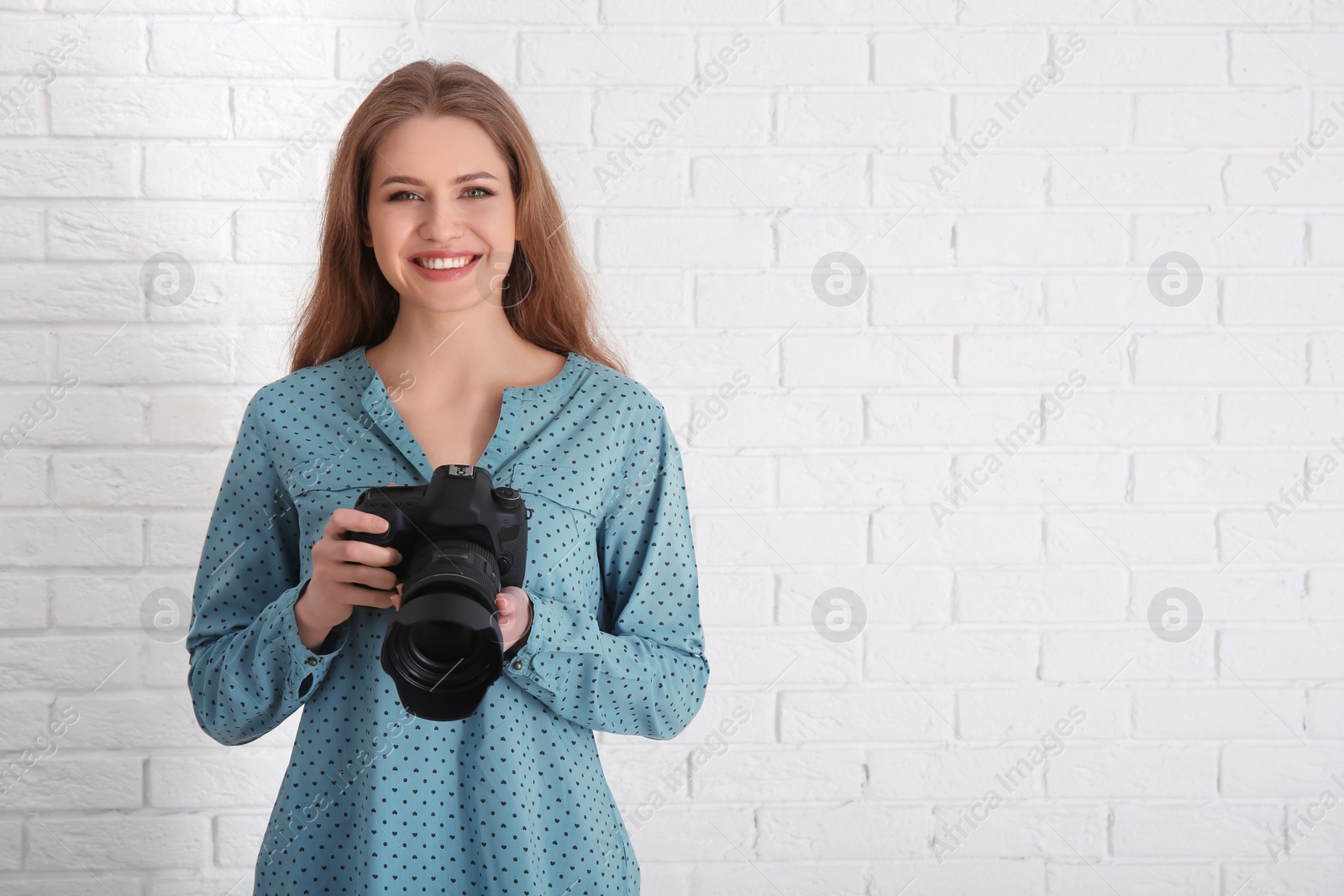 Photo of Female photographer with camera on brick background