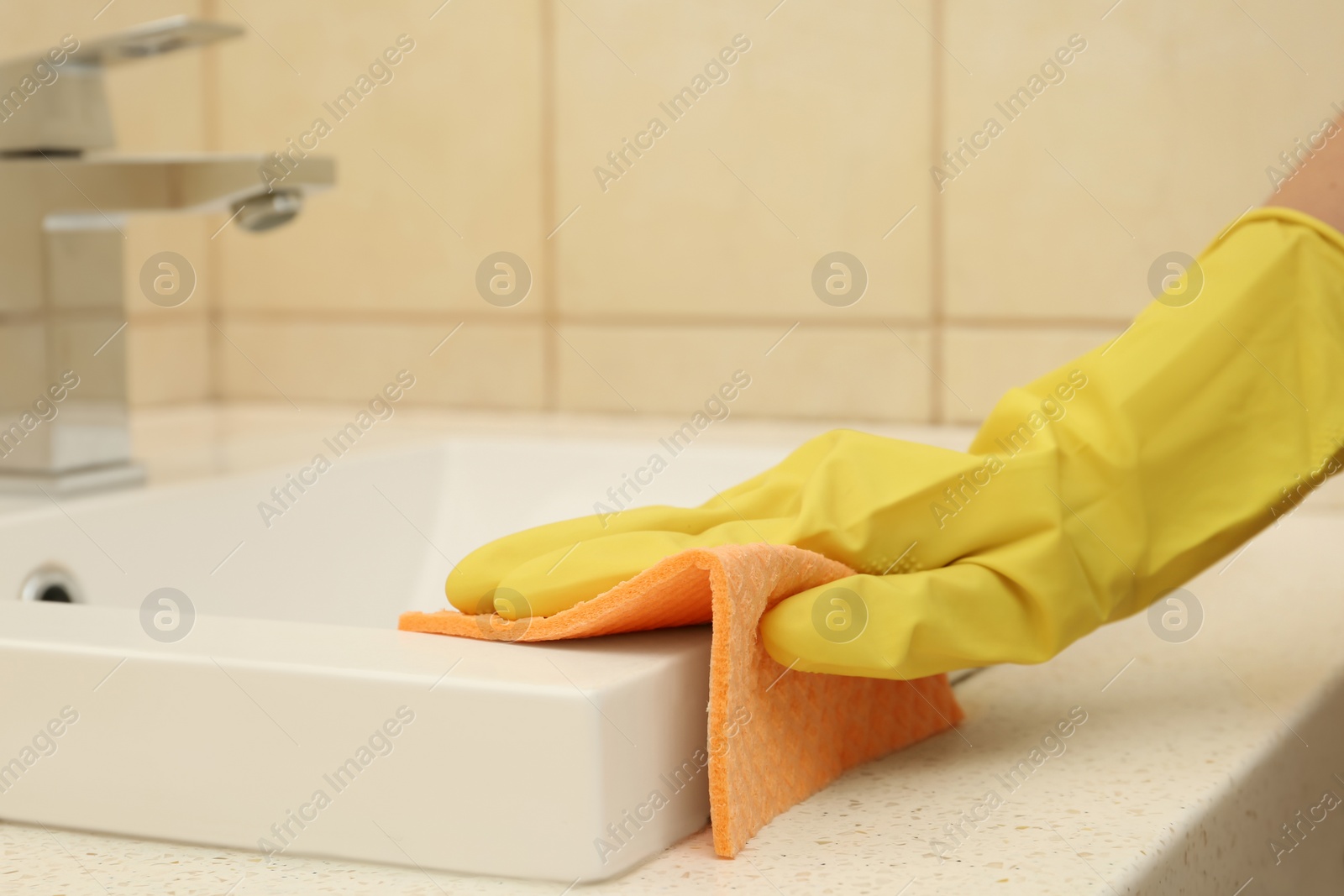 Photo of Woman cleaning sink with rag in bathroom, closeup