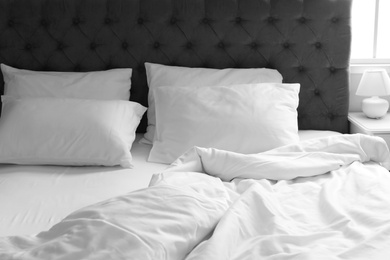 Photo of Comfortable bed with white linen and pillows at home