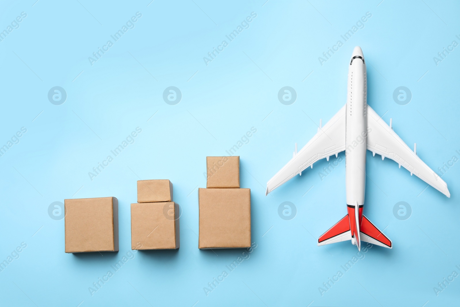 Photo of Top view of toy plane with boxes on blue background. Logistics and wholesale concept