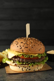 Photo of Burger with delicious patty on gray table against dark background