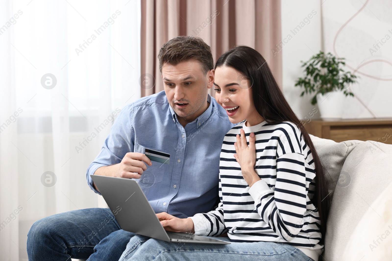 Photo of Happy couple with laptop and credit card shopping online together at home