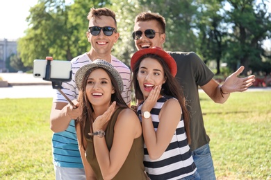 Photo of Group of young people taking selfie with monopod outdoors