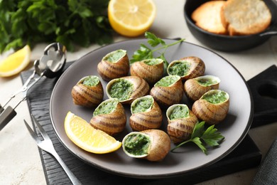 Photo of Delicious cooked snails served on light table