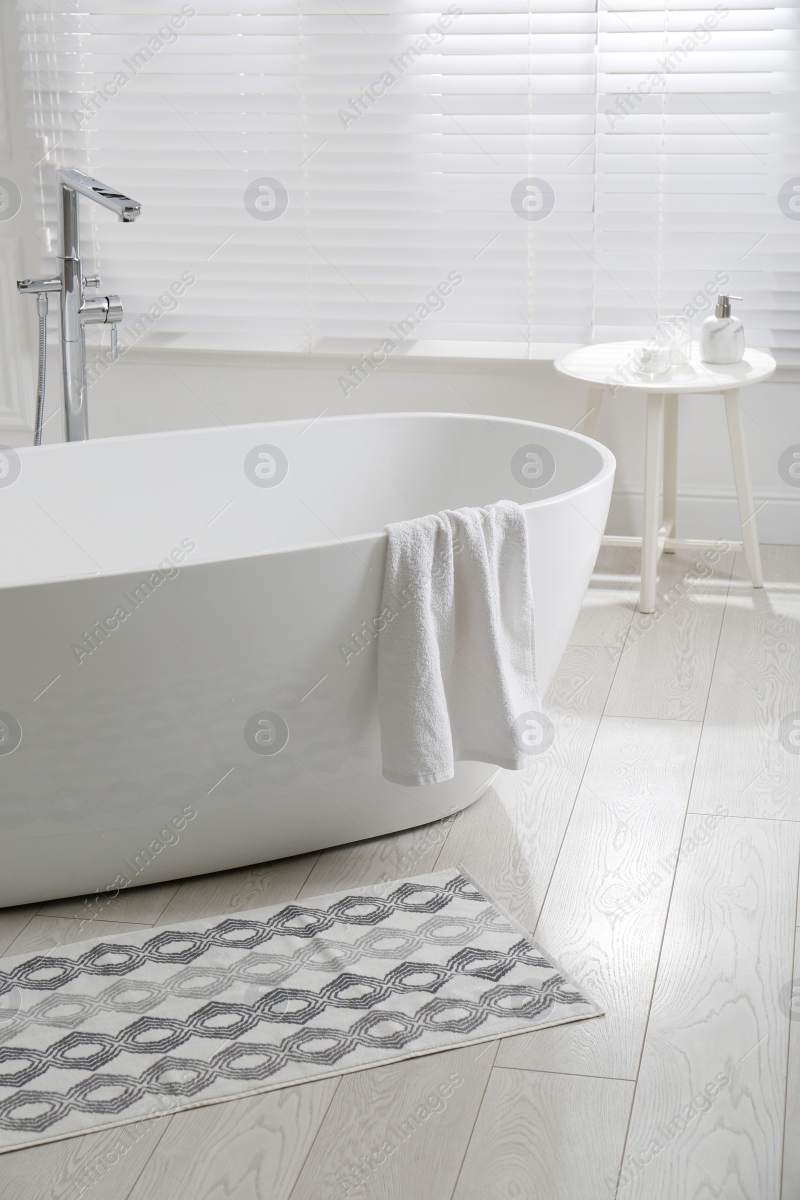 Photo of Stylish mat on floor near tub in bathroom. Interior design