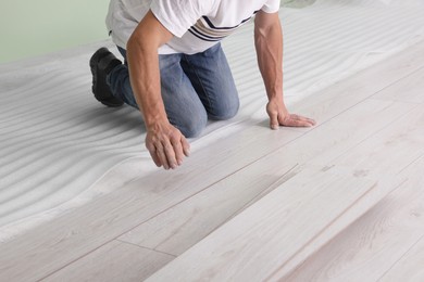 Photo of Man installing new laminate flooring indoors, closeup