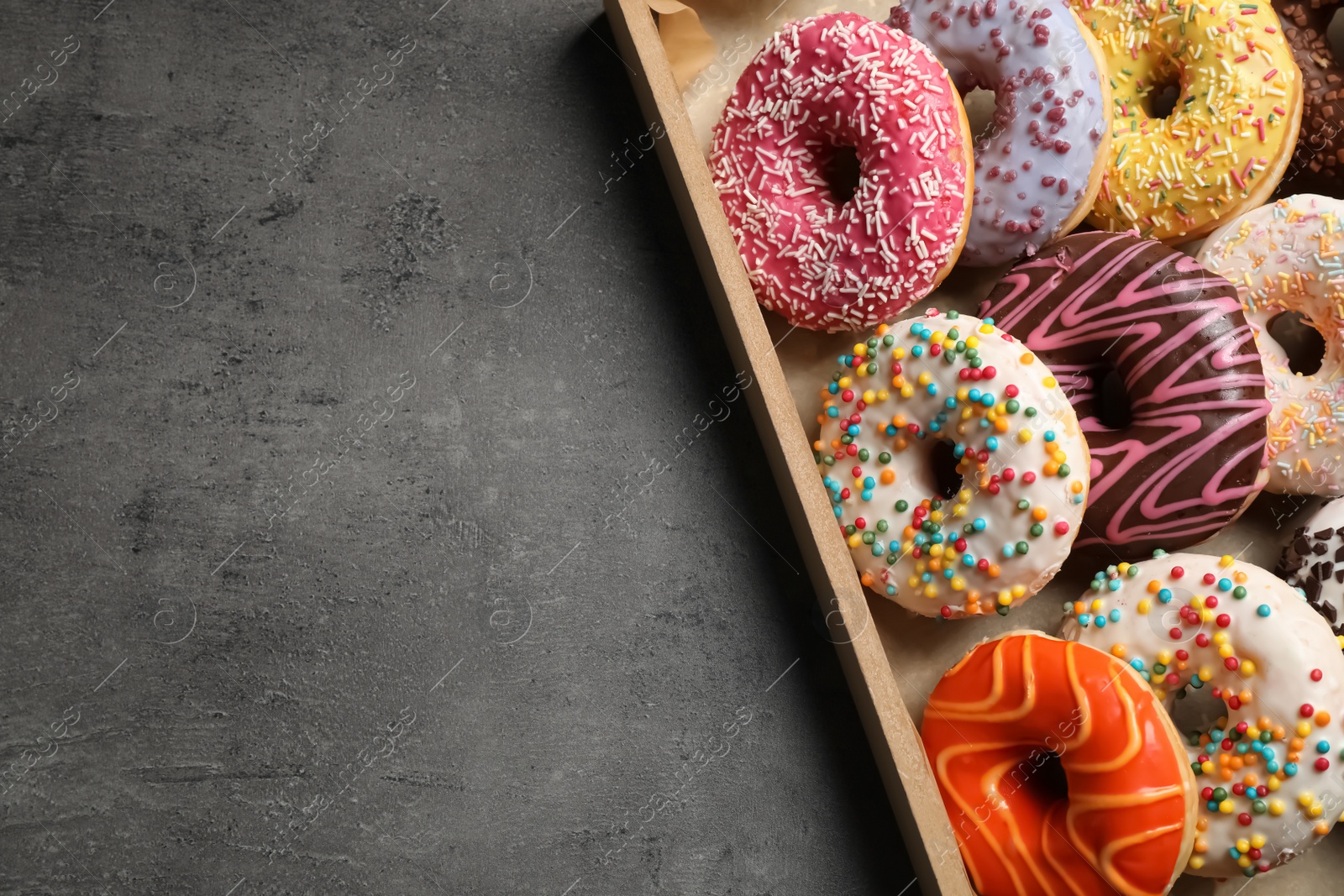 Photo of Top view of yummy donuts with sprinkles in box, space for text