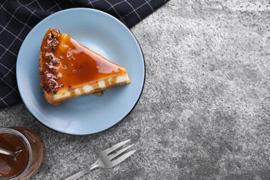 Photo of Piece of delicious cake with caramel served on grey table, flat lay. Space for text