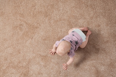 Cute little baby crawling on carpet indoors, top view with space for text