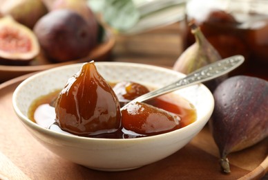 Photo of Bowl of tasty sweet fig jam on wooden table, closeup