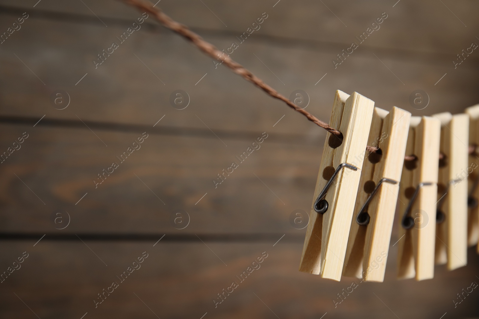 Photo of Many clothespins on rope against wooden background. Space for text