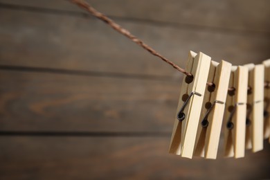 Many clothespins on rope against wooden background. Space for text