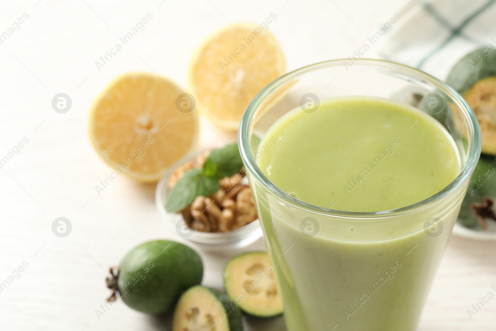 Photo of Fresh feijoa smoothie in glass on light table, closeup. Space for text