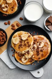 Tasty pancakes with sliced banana served on light grey table, flat lay