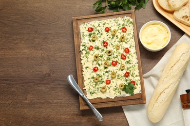 Photo of Fresh natural butter board with cut olives, bread and knife on wooden table, flat lay. Space for text