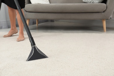 Photo of Woman removing dirt from carpet with vacuum cleaner indoors, closeup. Space for text