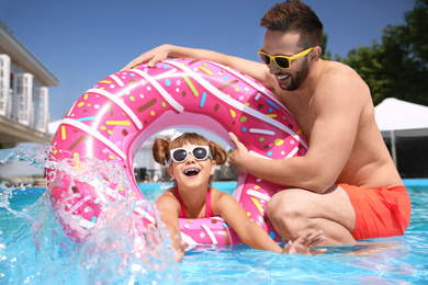 Photo of Father and daughter having fun in swimming pool. Family vacation