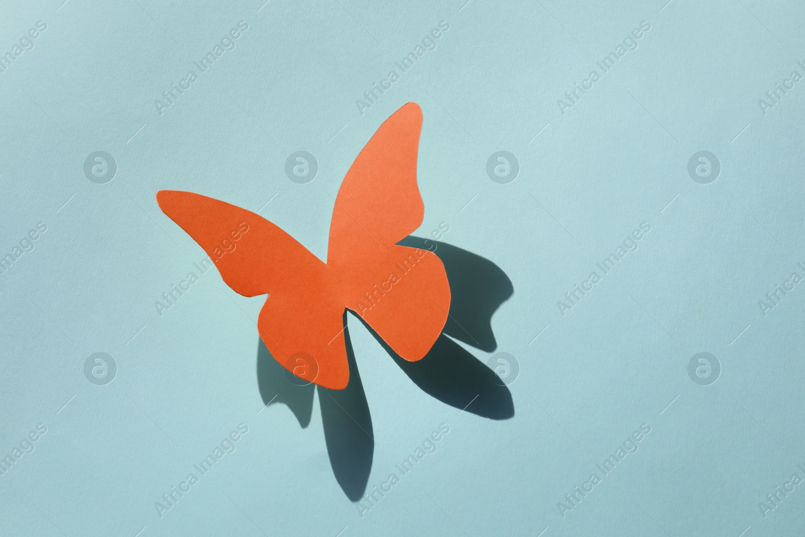 Image of Bright orange paper butterfly on light blue background