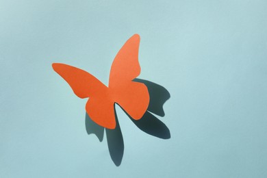 Bright orange paper butterfly on light blue background