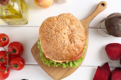 Photo of Delicious vegetarian burger and ingredients on white wooden table, flat lay