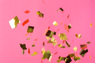 Shiny golden confetti falling down on pink background