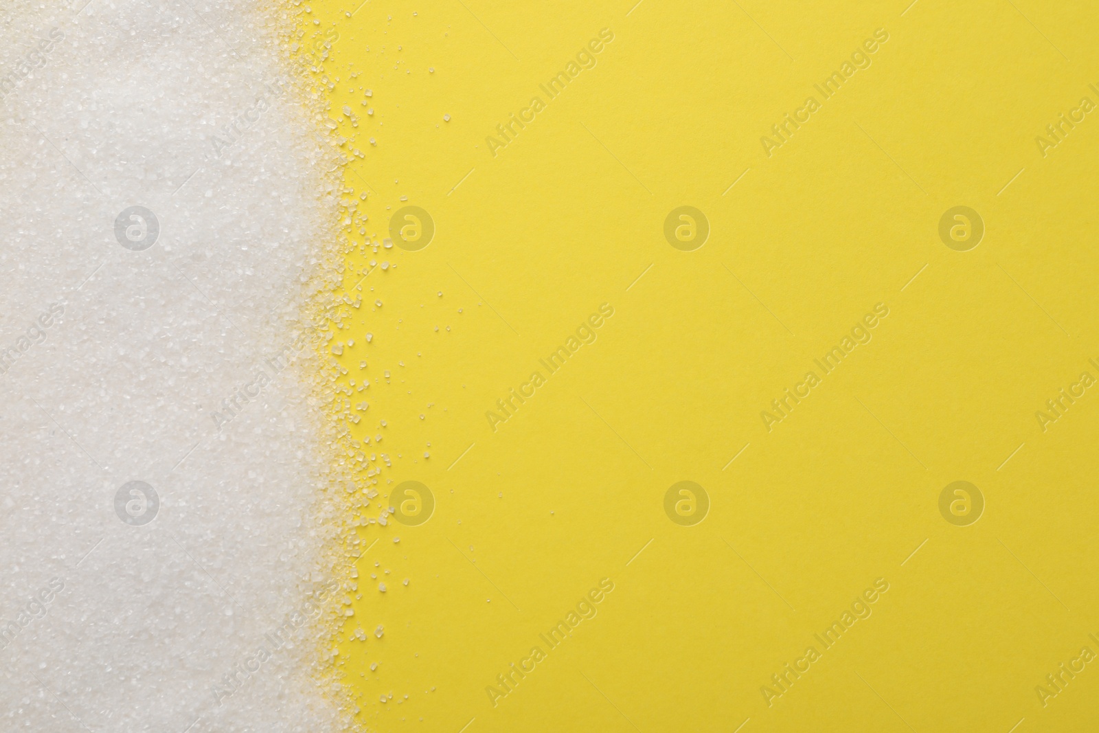 Photo of Granulated sugar on yellow background, top view. Space for text