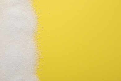 Granulated sugar on yellow background, top view. Space for text