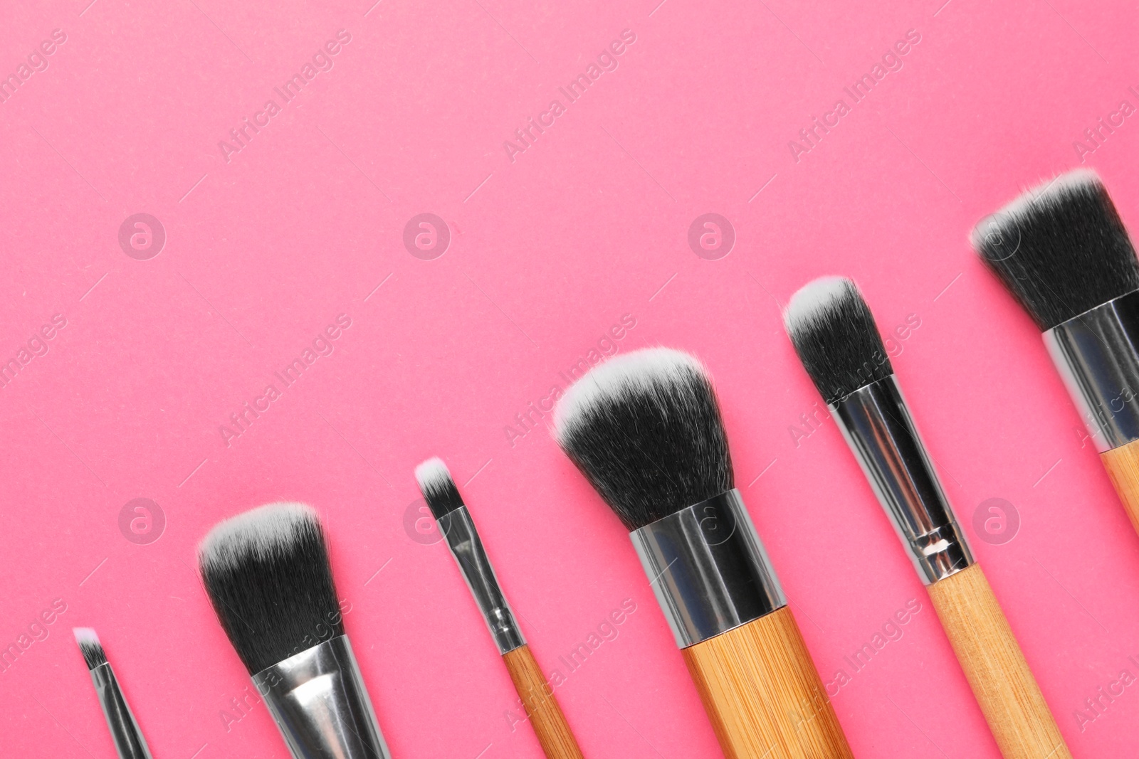 Photo of Set of makeup brushes on pink background, flat lay. Space for text