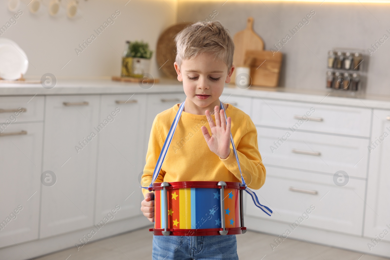 Photo of Little boy playing toy drum in kitchen