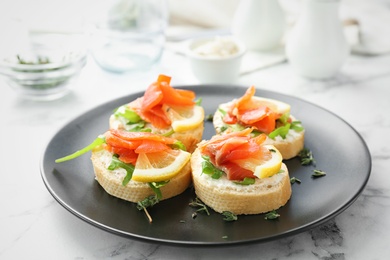 Plate of tasty sandwiches with fresh sliced salmon fillet on table