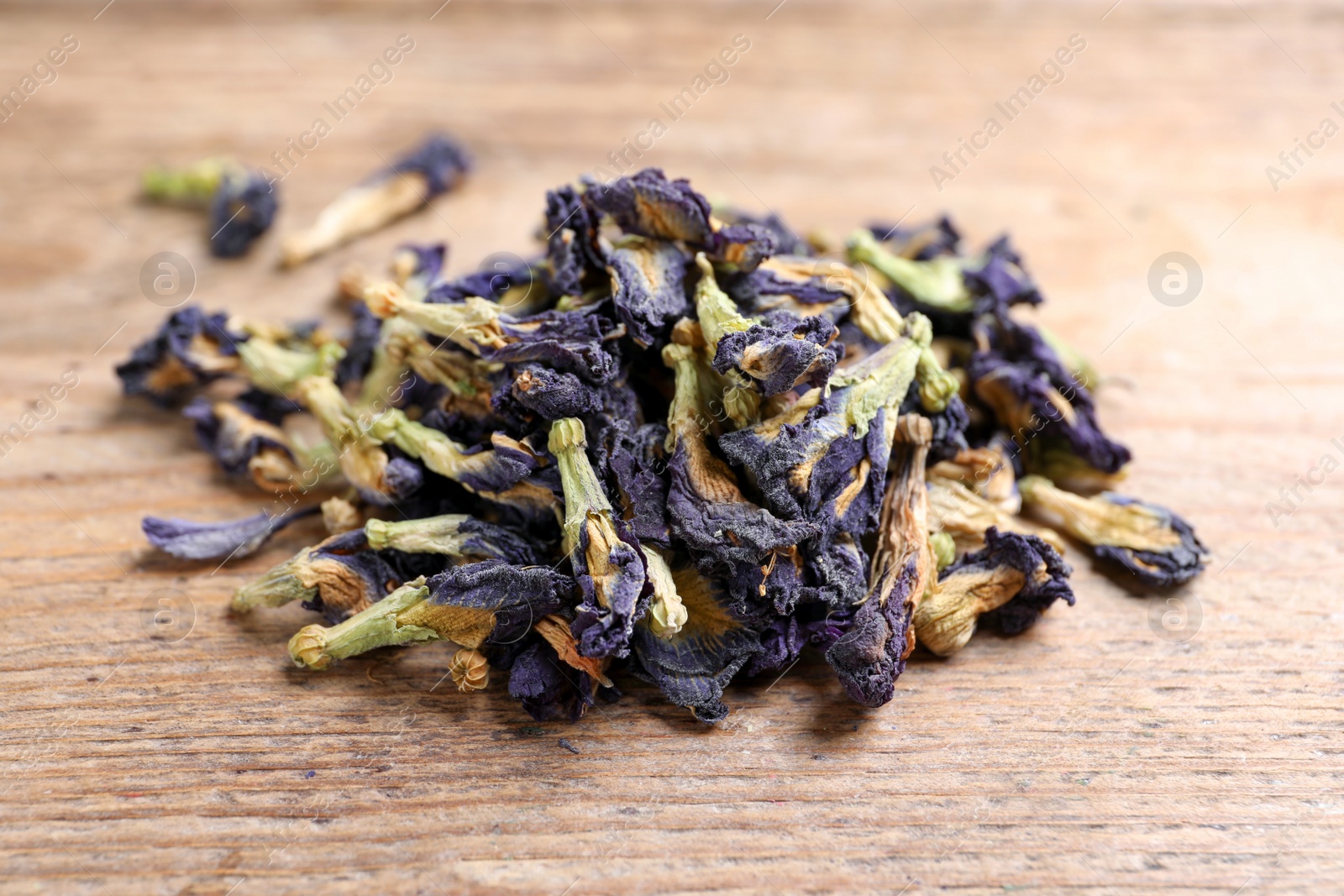 Photo of Pile of dry organic blue Anchan on wooden table, closeup. Herbal tea