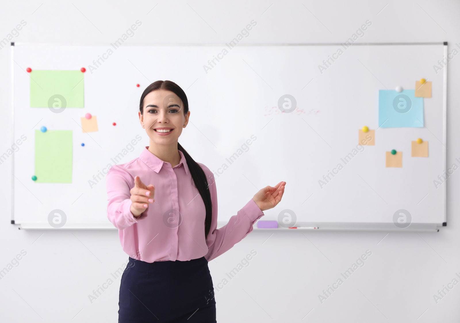 Photo of Young teacher near whiteboard in modern classroom. Space for text