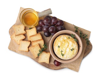 Photo of Tasty baked camembert in bowl, croutons, grapes, honey and thyme on white background, top view