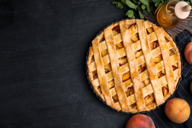 Photo of Delicious peach pie and fresh fruits on black table, flat lay. Space for text