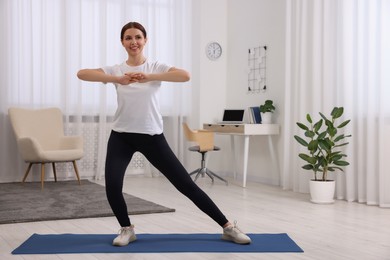 Happy woman doing morning exercise at home, space for text