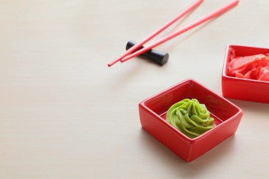 Swirl of wasabi paste, pickled ginger and chopsticks on white table, space for text