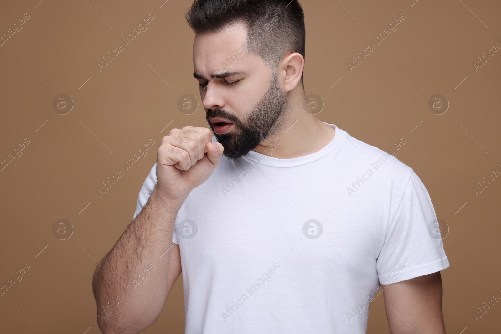 Photo of Sick man coughing on brown background. Cold symptoms